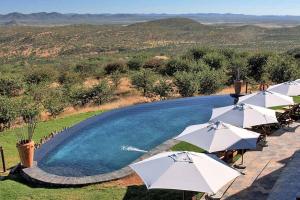 a swimming pool with white umbrellas next to a pool at Opuwo Country Lodge in Opuwo