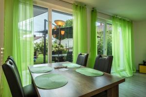 a dining room with a wooden table and green curtains at Ferienwohnung Jasmin in Sipplingen