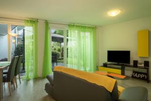 a living room with green curtains and a couch and a television at Ferienwohnung Jasmin in Sipplingen