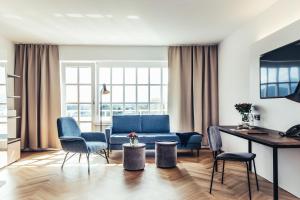 a living room with a blue couch and chairs at Hotel Dermuth Klagenfurt in Klagenfurt