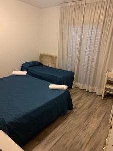 a bedroom with two beds and a window with curtains at Hotel Piada D'Oro in Riccione