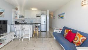 a living room with a blue couch and a kitchen at Ocean Breeze at 92 Chaka Cove in Ballito