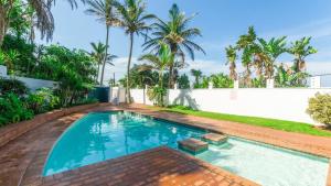 a swimming pool in the backyard of a house with palm trees at Ocean Breeze at 92 Chaka Cove in Ballito