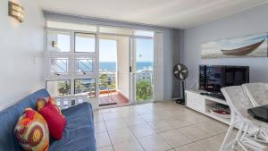 a living room with a blue couch and a television at Ocean Breeze at 92 Chaka Cove in Ballito