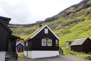 a black and white building with a hill in the background at holiday cottage in Tjørnuvík in Tjørnuvík