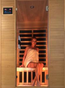 a woman sitting on a bed in a room at Mandula Apartman in Cegléd