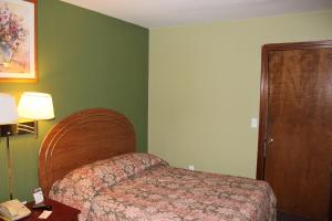 a hotel room with a bed and a telephone at Oak Hill Inn and Suites in Tahlequah