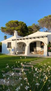 une maison blanche avec un arbre en arrière-plan dans l'établissement BiniFa - Lovely luxury villa few steps from the sea, à Binibeca