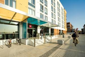 una persona montando una bicicleta delante de un edificio en ibis Bristol Temple Meads, en Bristol