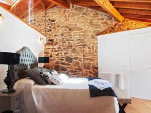 um quarto com uma cama com uma parede de pedra em A Forxa Casa Ferrador Ribeira Sacra em Sober