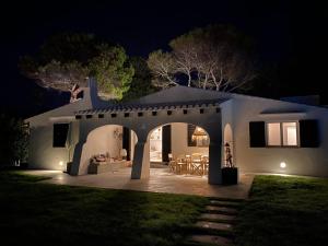 - une maison blanche avec terrasse la nuit dans l'établissement BiniFa - Lovely luxury villa few steps from the sea, à Binibeca