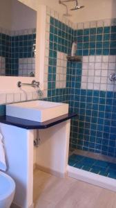 une salle de bain avec un lavabo et une douche avec du carrelage bleu dans l'établissement Appartamenti del Comandante, à Santa Marina Salina