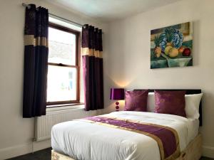 a bedroom with a bed with purple curtains and a window at 3 bedroomed house for up to 7 people, close to The Hoe, Barbican & City Centre in Plymouth