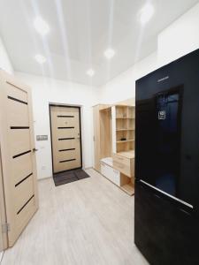 サマラにあるУютная квартира с камином в новом домеの黒い冷蔵庫と木製のキャビネットが備わる客室です。