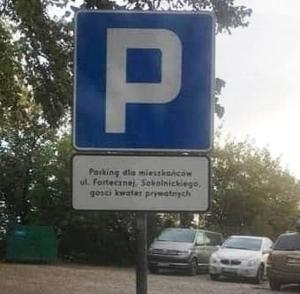 a blue parking sign with cars parked in a parking lot at Zielone Wzgórze na Starówce in Sandomierz