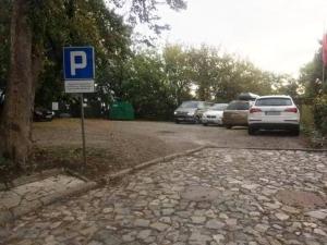 a parking lot with parked cars and a blue parking sign at Zielone Wzgórze na Starówce in Sandomierz