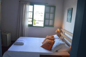 a bedroom with a white bed with a window at Pousada Baluarte in Salvador