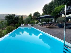 a blue swimming pool with chairs and an umbrella at Casa da Horta in Peso da Régua