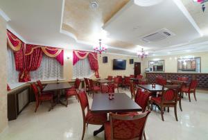 un restaurante con mesas de madera y sillas rojas en Prestige House Verona Hotel en Kazán