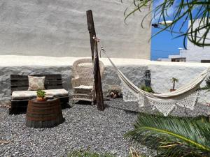 a patio with a hammock and a chair and a table at Casa emblemática Buenavista del Norte in Buenavista del Norte