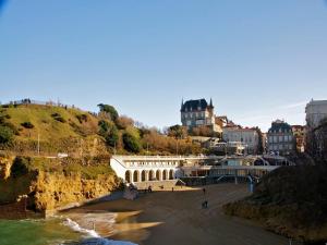 a beach with a castle on top of a hill at Hotel Marbella in Biarritz