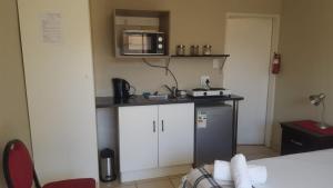 a small kitchen with a microwave and a refrigerator at Dumelang Executive Lodge- OFF-GRID Solar powered Midrand in Midrand +52 photos