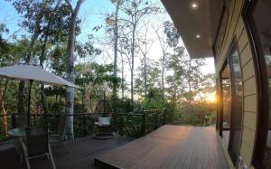 eine Veranda eines Hauses mit einem Tisch und einem Sonnenschirm in der Unterkunft Selva Color - Forest & Beach EcoLodge in Quebrada Ganado