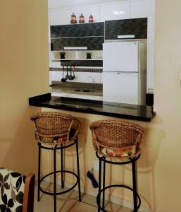 a kitchen with two bar stools and a white refrigerator at Apto 2 quartos em Arroio do Silva in Arroio do Silva