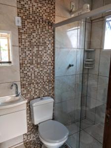 a bathroom with a toilet and a glass shower at Aluguel casa Bombinhas in Bombinhas