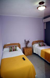 a bedroom with two beds with yellow sheets at Hostal Asturias in Jarilla