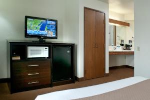 a hotel room with a television on top of a dresser at AmericInn by Wyndham Green Bay West in Green Bay