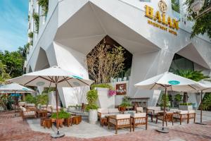 ein Restaurant mit Tischen und Sonnenschirmen vor einem Gebäude in der Unterkunft HAIAN Riverfront Hotel Da Nang in Đà Nẵng