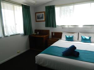 a bedroom with a bed with a blue pillow on it at Coachman Motel in Toowoomba +40 photos