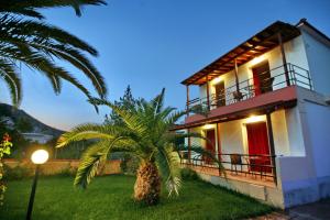 una casa con una palmera delante de ella en Andriotis Studios, en Skála Loutrón