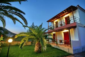 a house with a palm tree in front of it at Andriotis Studios in Skála Loutrón