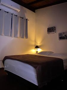 1 dormitorio con 1 cama y 1 lámpara en una habitación en Pousada Morrison, en Praia do Rosa