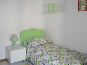 a bedroom with a bed with a green headboard and a night stand at Casa Vacanze Trapani Vico compagni in Trapani