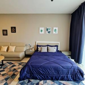 a bedroom with a blue bed and a couch at Ellkay Studio Suite at Evo Bangi in Kampong Sungai Ramal Dalam