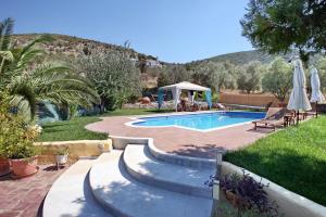 a swimming pool with a table and a gazebo at Andriotis Rooms & Houses in Skála Loutrón