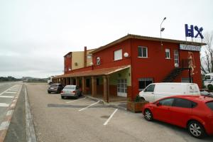 un edificio rojo con coches estacionados en un estacionamiento en Hostal Asturias, en Jarilla