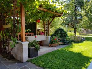 a garden with a pergola with a bench and flowers at Haus Obermoser in Dellach im Drautal