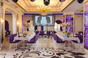 a banquet room with tables and purple chairs and a screen at Denart Hotel in Sochi
