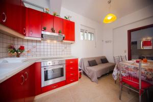 a kitchen with red cabinets and a table and a couch at Stegnailion in Archangelos
