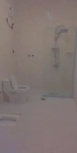 a white bathroom with a shower and a toilet at شاليهات لودج in Al Humaizah
