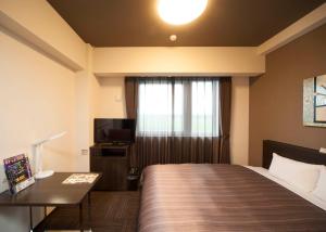 Hotel Route-Inn Ishioka في Ishioka: غرفه فندقيه سرير وتلفزيون
