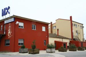 a red building with potted plants in front of it at Hostal Asturias in Jarilla