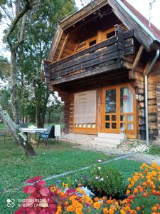 a log cabin with a table and flowers in front of it at Apartman egy Makovecz Imre tervezte házban in Ispánk