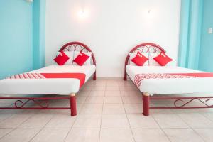 two beds in a room with red and white pillows at OYO Hotel Estacion,José Cardel,Parque Central Revolución in José Cardel