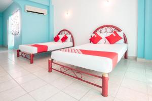2 camas con almohadas rojas y blancas en una habitación en OYO Hotel Estacion,José Cardel,Parque Central Revolución, en José Cardel