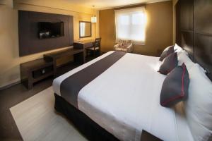 um quarto de hotel com uma cama grande e uma televisão em Collection O Las Iglesias, Cholula em Cholula